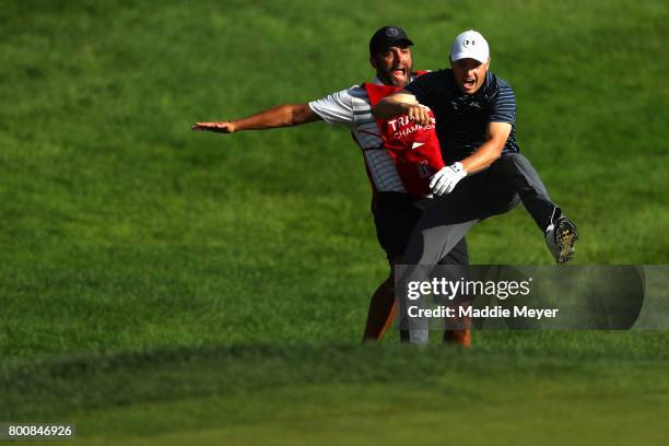 Jordan Spieth of the United States celebrates with caddie Michael Greller after chipping in for birdie from a bunker on the 18th green to win the...