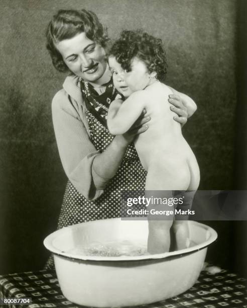 mother washing daughter in small basin on table - baby bottom stock pictures, royalty-free photos & images