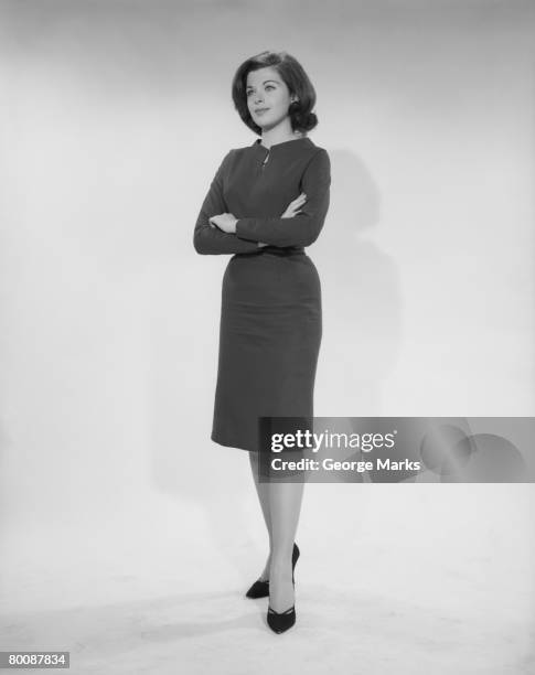 woman standing with arms crossed, studio shot - años 60 fotografías e imágenes de stock