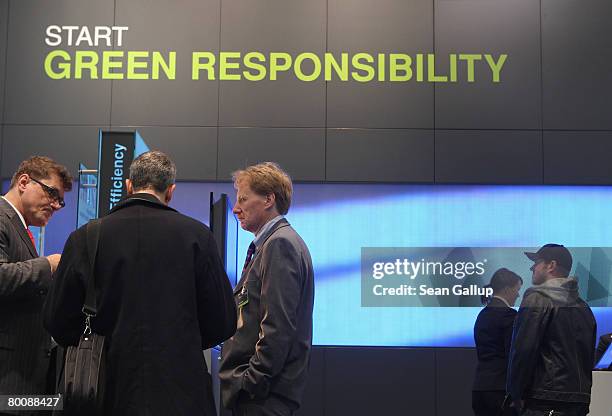 Visitors look at products under a sign promoting a more green-oriented philosophy at the IBM stand at the CeBIT technology fair a day before the...