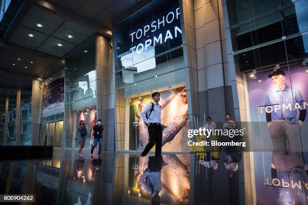 Pedestrians walk past advertising in the windows of a Topshop store, operated by Arcadia Group Ltd., outside the CentralWorld shopping mall in...