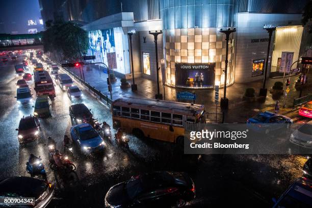 Vehicles pass through an intersection in the rain outside the Gaysorn shopping mall at night in Bangkok, Thailand, on Wednesday, June 21, 2017....