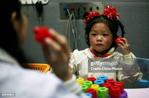 Teacher trains hearing-impaired children with a drum at the Hearing and Language Rehabilitation Center for the Deaf Children of Chongqing Disabled...