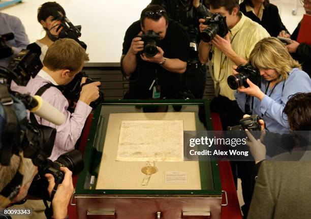 Photographers point their cameras to a 1297 version of Magna Carta during a press viewing of the document at the National Archives March 3, 2008 in...