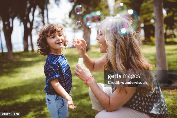 abuela y nieto riendo y soplar burbujas en el parque - bubbles happy fotografías e imágenes de stock