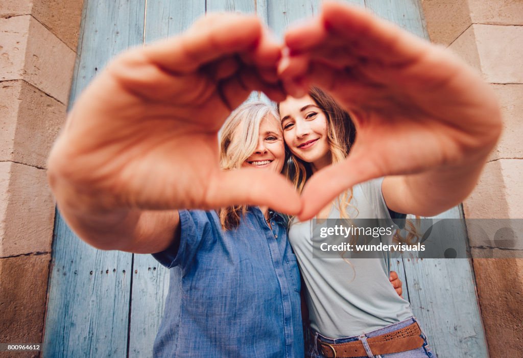 Smiling senior mother and daughter making a heart shape with their hands