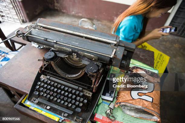 Woman uses a smartphone while sitting next to a typewriter in Yangon, Myanmar, on Friday, June 16, 2017. A pariah state for decades, Myanmars recent...