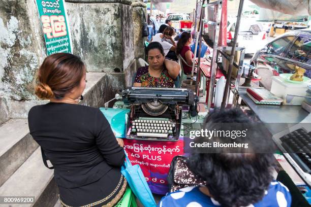 Customers sit next to a typist working on a typewriter in Yangon, Myanmar, on Friday, June 16, 2017. A pariah state for decades, Myanmars recent...
