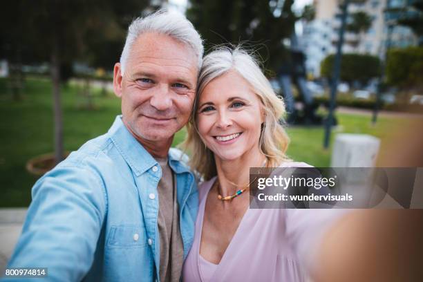 mature husband and wife taking selfies together in the city - two lovers photocall stock pictures, royalty-free photos & images