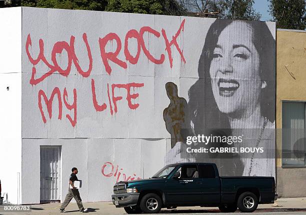 Man walks near a mural showing French actress Marion Cotillard receiving her best actress Oscars for "La Mome", on a wall in Los Angeles, California...