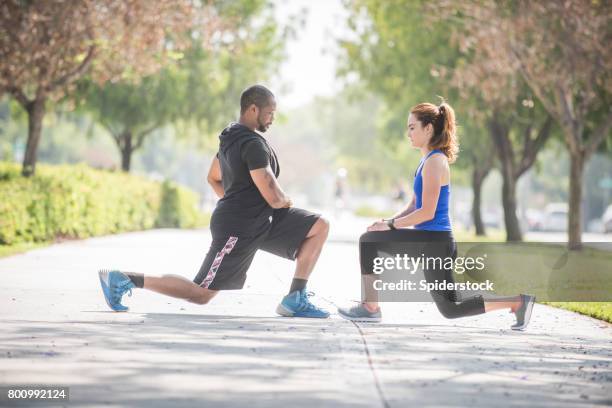 personal trainer doing deep knee bends with client - knee bend stock pictures, royalty-free photos & images