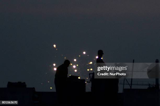 Indian muslims stand on roof top of a building to sight moon ,near decorated jama Masjid , on the eve of Eid al-Fitr festival , in Allahabad on June...