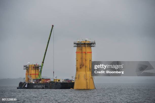 Barge positions the yellow 100 ton bases for offshore floating wind turbines during assembly in the Hywind pilot park, operated by Statoil ASA, in...