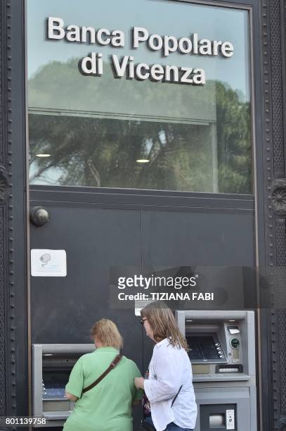 Women use an ATM of Italian bank "Banca Popolare di Vicenza" at Piazza Venezia in central Rome on June 26, 2017. Up to 3,900 voluntary redundancies...