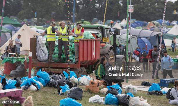 Rubbish is collected in front of the Pyramid Stage as festival goers leave the Glastonbury Festival site at Worthy Farm in Pilton on June 26, 2017...