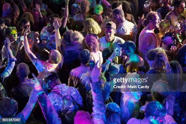 People participate in a UV paint fight at a late night venue at the Glastonbury Festival site at Worthy Farm in Pilton on June 26, 2017 near...