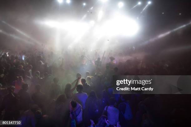 People participate in a UV paint fight at a late night venue at the Glastonbury Festival site at Worthy Farm in Pilton on June 26, 2017 near...