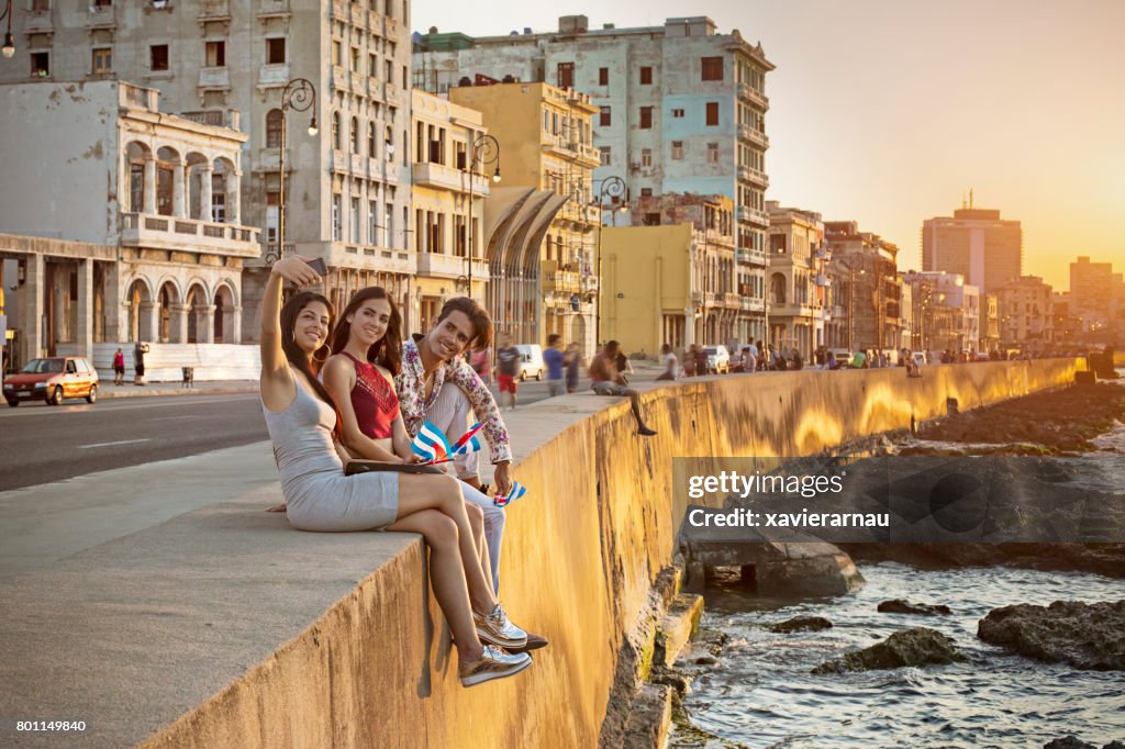 Friends taking selfie on retaining wall in Havana