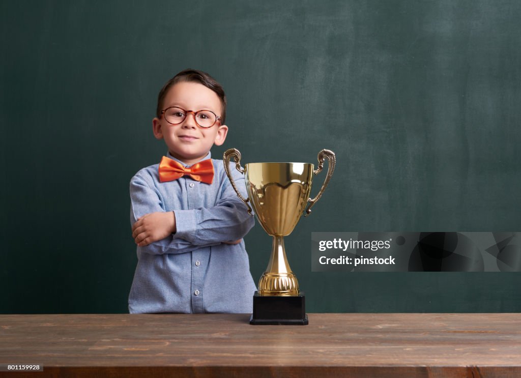 Nettes Kind mit einer goldenen Trophäe