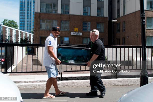 Resident is helped as he carries a fish tank out of Taplow Tower residential block on the Chalcots Estate in north London on June 26, 2017 as...