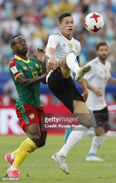 Julian Draxler of Germany tries to hold off Christian Bassogog of Cameroon during the first half of a Group B match at the Confederations Cup in...