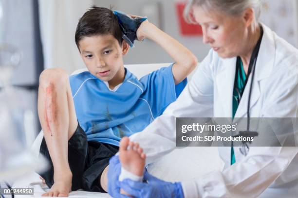 emergency room doctor examines injured soccer player - head wound stock pictures, royalty-free photos & images