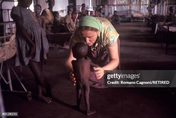 Doctor Ann Seymour helps an emaciated child, barely able to stand on his legs, to walk in Biafra, a secessionist state in southern Nigeria, circa...