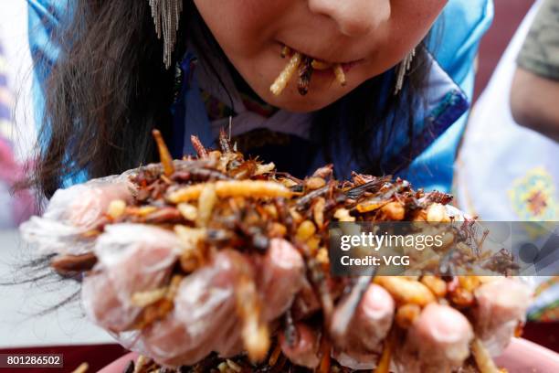 Tourists eat fried insects, including locusts, bamboo worms, dragonfly larvae, silkworm chrysalises and so on, during a competition at a scenic spot...