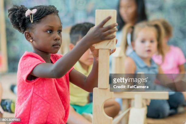 girl stacks blocks at preschool - wood block stacking stock pictures, royalty-free photos & images
