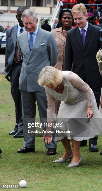 Camilla, Duchess of Cornwall, watched by Prince Charles, Prince of Wales, tries her hand with a cricket ball during a visit to Queen's Park Cricket...