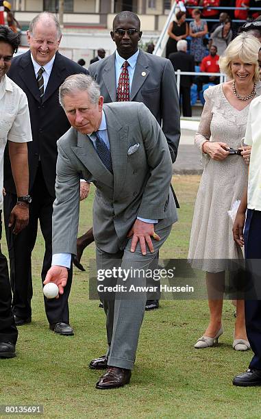 Prince Charles, Prince of Wales, watched by Camilla, Duchess of Cornwall, tries his hand with a cricket ball during a visit to Queen's Park Cricket...