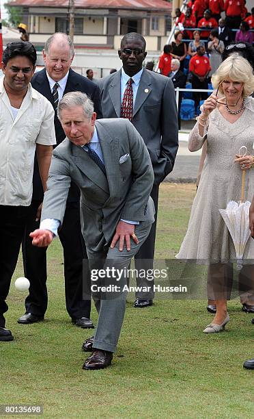 Prince Charles, Prince of Wales, watched by Camilla, Duchess of Cornwall, tries his hand with a cricket ball during a visit to Queen's Park Cricket...