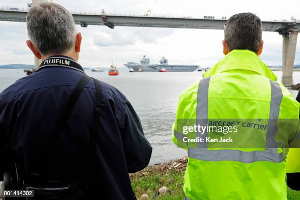 Spectators on the shores of the Forth Estuary watch the aircraft carrier HMS Queen Elizabeth leave Rosyth dockyard to begin sea trials, with the new...
