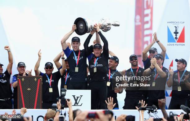 Emirates Team New Zealand helmsman Peter Burling and skipper Glenn Ashby receive the "Auld Mug" trophy after winning the America's Cup Match...