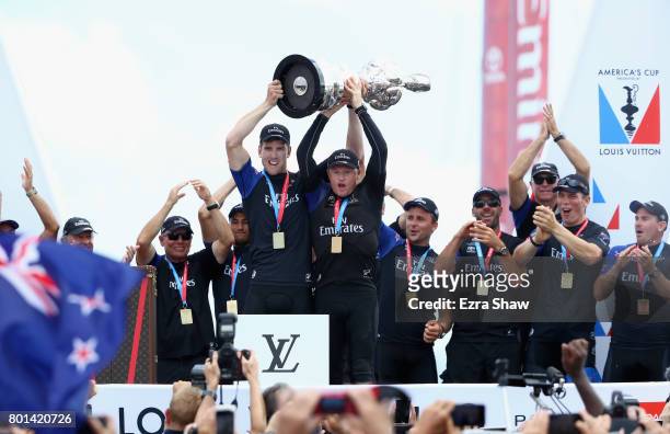 Peter Burling and Glenn Ashby of Emirates Team New Zealand lift the America's Cup trophy after they beat ORACLE TEAM USA on June 26, 2017 in...