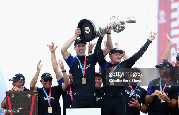 Peter Burling and Glenn Ashby of Emirates Team New Zealand lift the America's Cup trophy after they beat ORACLE TEAM USA on June 26, 2017 in...