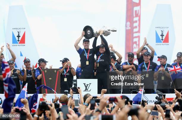 Peter Burling and Glenn Ashby of Emirates Team New Zealand lift the America's Cup trophy after they beat ORACLE TEAM USA on June 26, 2017 in...