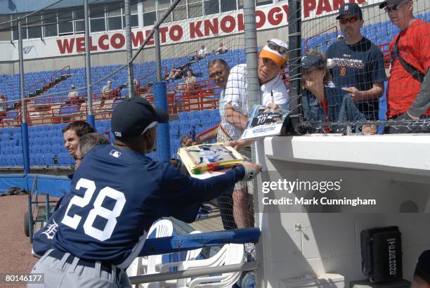 Curtis Granderson of the Detroit Tigers signs autographs for fans before the spring training game against the Toronto Blue Jays at Knology Park in...