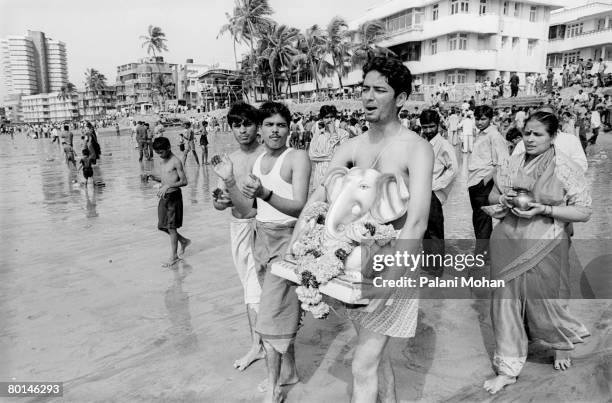 Devotees of the elephant god Ganesha carry statues of the deity to be immersed into the water at Chowpatty Beach October 2002 in Mumbai, India. Lord...