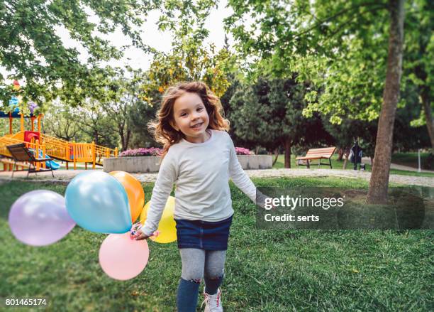 ragazza felice che gioca con un mazzo colorato di palloncini - children birthday party foto e immagini stock