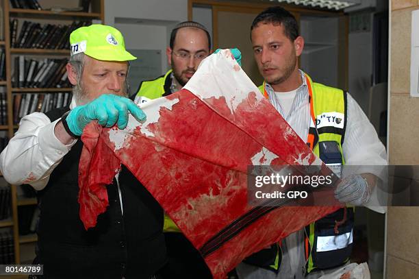 In this photo provided by the Israeli Government Press Office , volunteers from the ultra-Orthodox Zaka rescue organization hold up a victim's bloody...