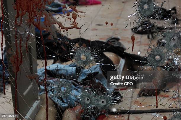 In this photo provided by the Israeli Government Press Office , a victim's body is seen behind a bullet-ridden and blood-stained glass door in the...