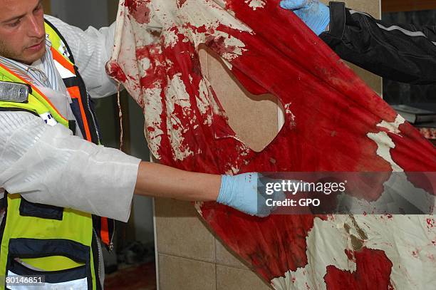 In this photo provided by the Israeli Government Press Office , a volunteer from the ultra-Orthodox Zaka rescue organization points out a bullet hole...