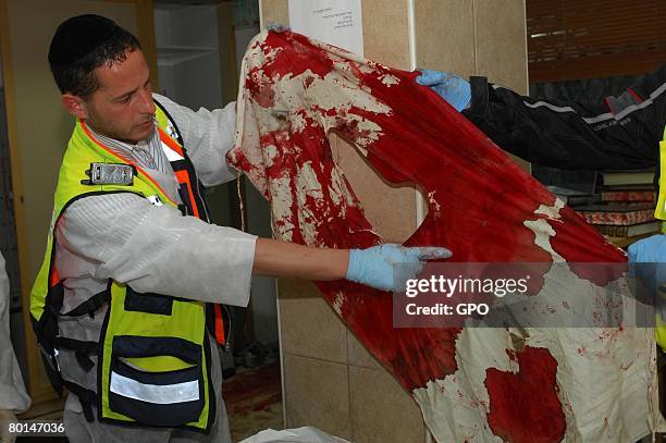 In this photo provided by the Israeli Government Press Office , a volunteer from the ultra-Orthodox Zaka rescue organization points out a bullet hole...