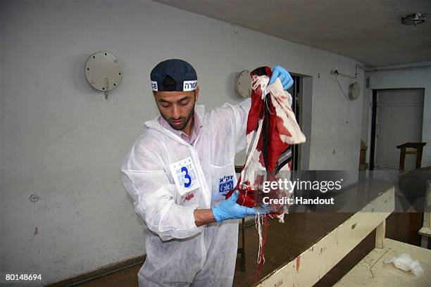 In this photo provided by the ultra-Orthodox ZAKA Jewish rescue organization, a ZAKA volunteer collects a victim's bloody prayer shawl in the library...