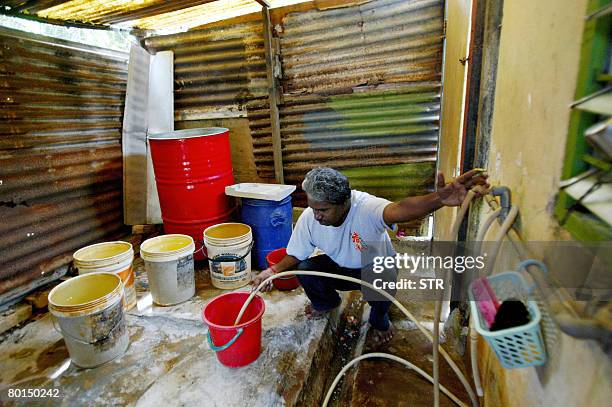 Malaysia-vote-Indians by M. Jegathesan Ethnic Indian T. Vijayan fills up buckets with water from a tank outside his residence at the Tuan Mee oil...
