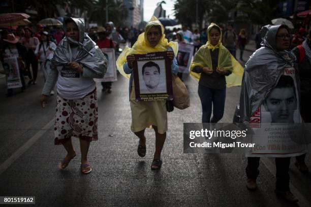 Relatives of the 43 missing students of Ayotzinapa wearing playstic caps march during a demonstration to commemorate the 1000 days anniversary of the...