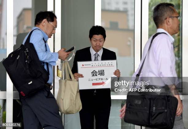 An staff member holds a placard leading shareholders to the venue of the annual shareholders' meeting of Japan's crisis-hit car parts maker Takata in...