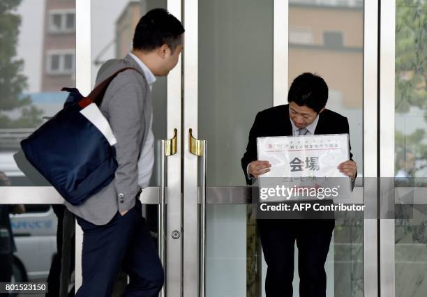 Staff member holds a placard guiding shareholders to the venue of the annual shareholders' meeting of Japan's crisis-hit car parts maker Takata in...