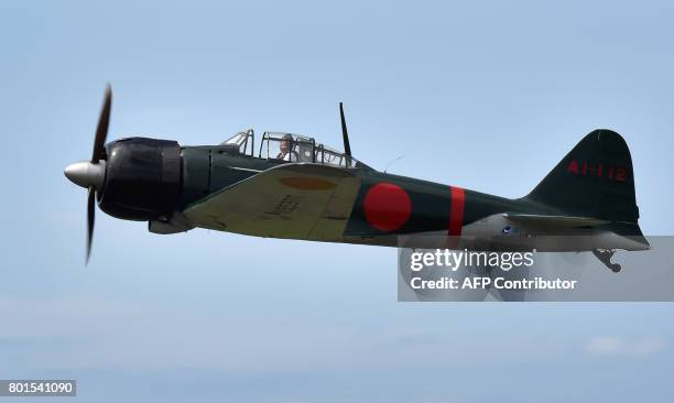 This picture taken on June 9, 2017 shows a restored World War II-era Mitsubishi A6M Type 22 Zero fighter flying over an airfield in Ryugasaki,...